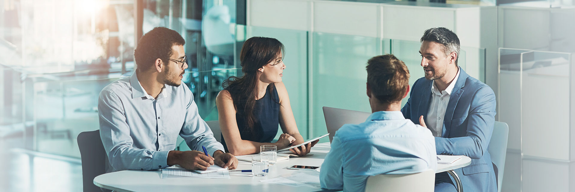 AdobeStock_1131753876 Réunion d'équipe sur une table blanche regroupant 4 collaborateurs
